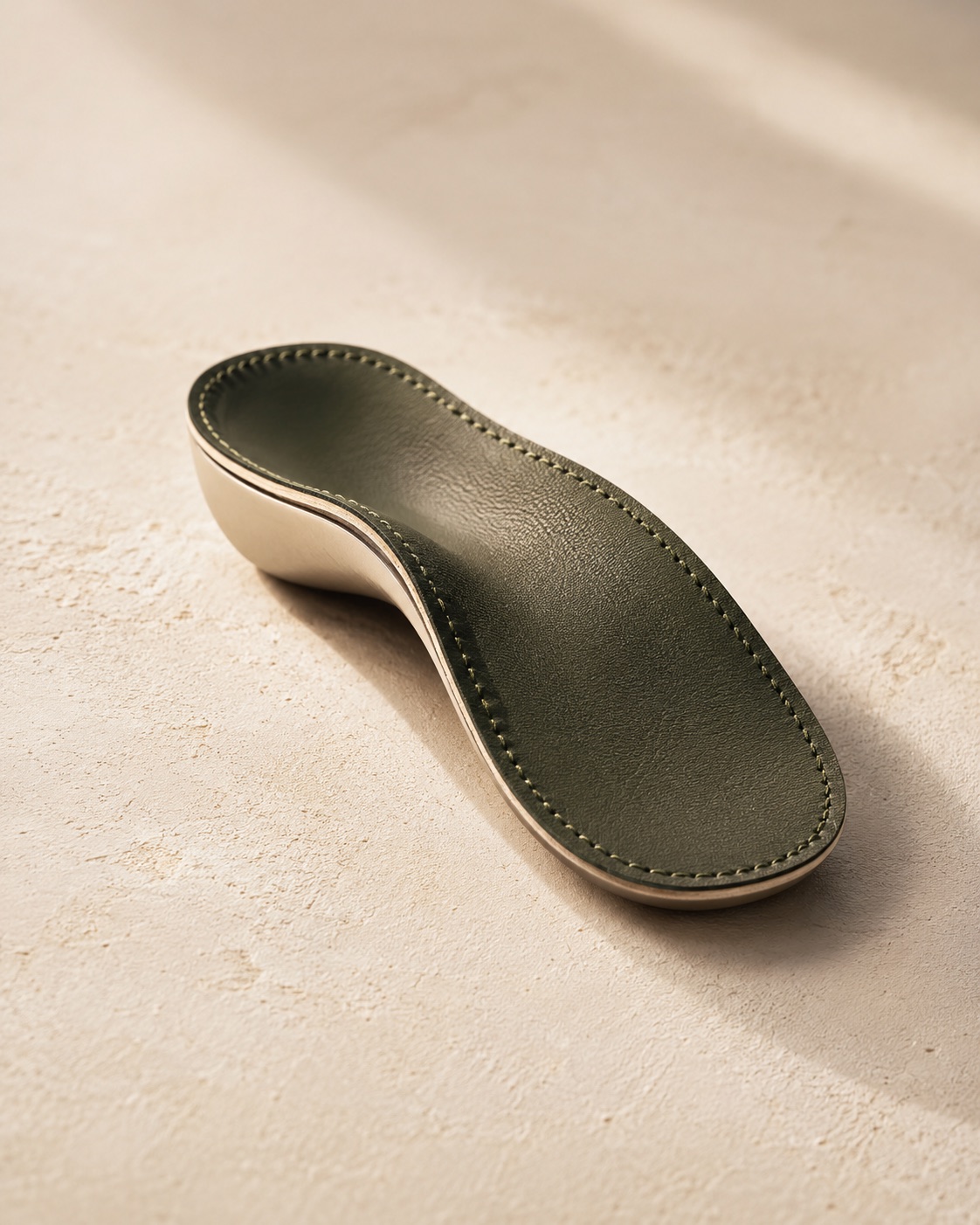 A custom orthotic photographed close, on a warm neutral surface